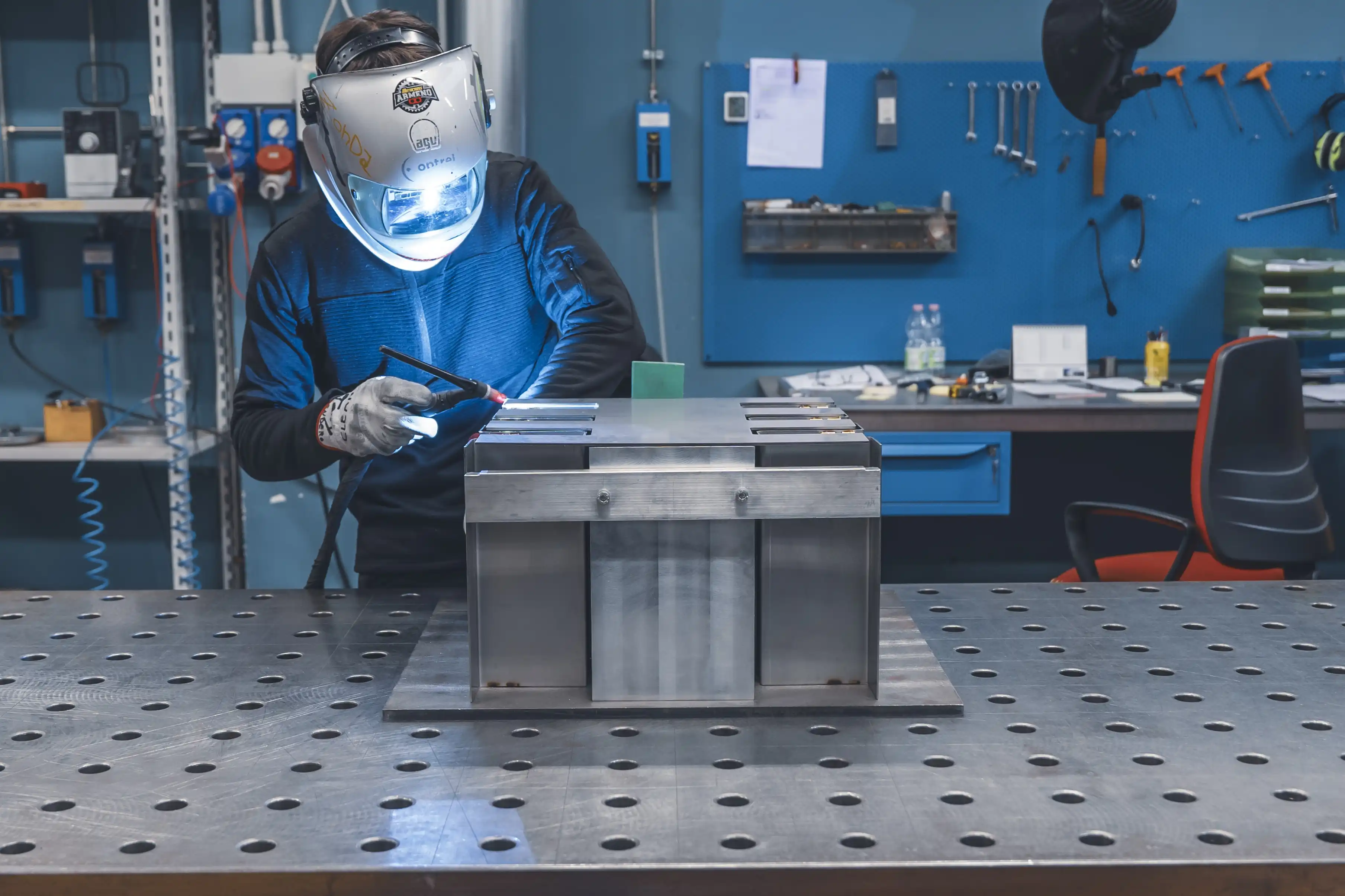 Operatore con maschera protettiva al lavoro su banco di saldatura OMV