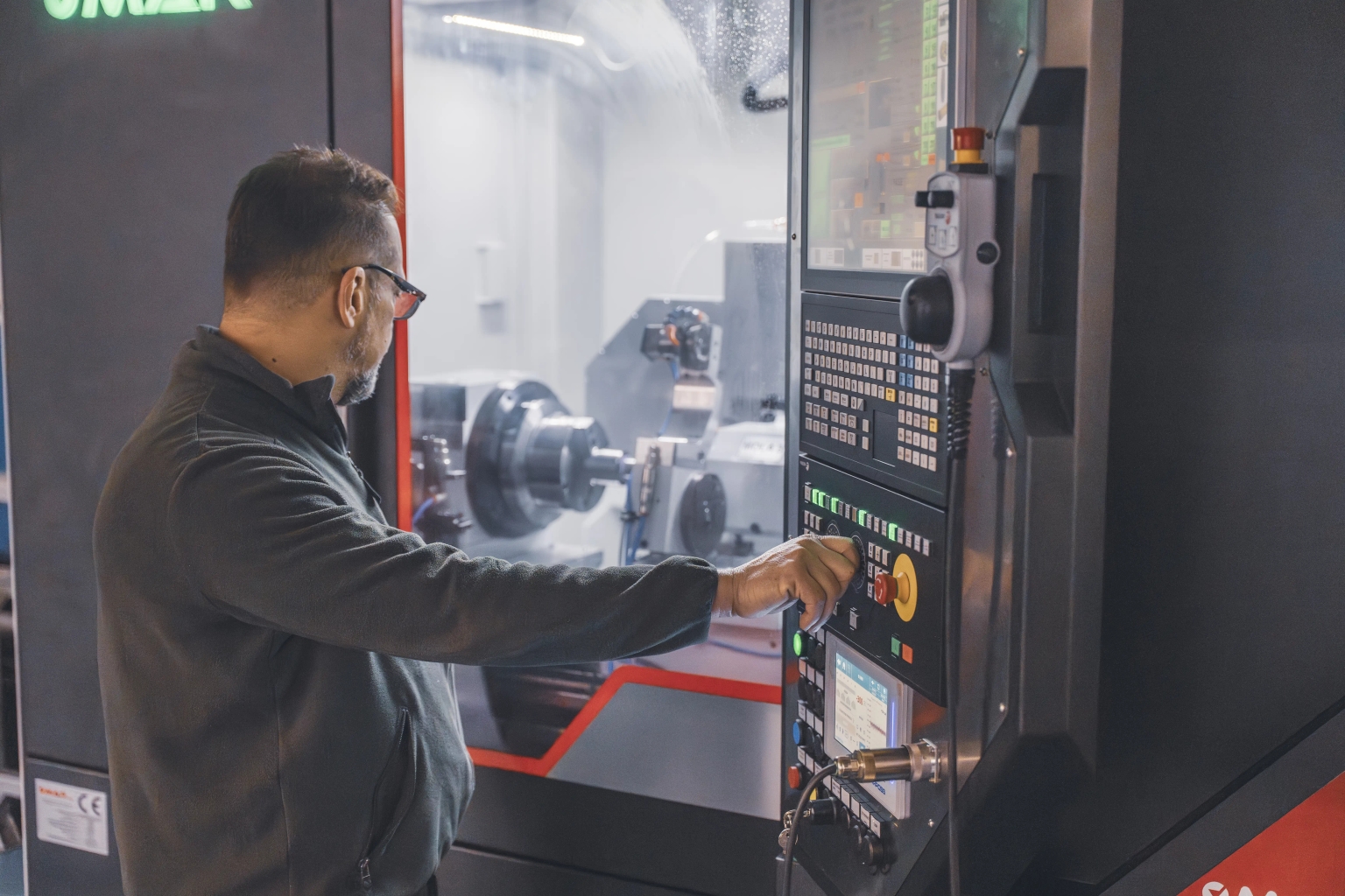 Operatore al pannello di controllo di un tornio CNC nel reparto produzione OMV